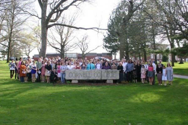 People standing behind the Cornell sign