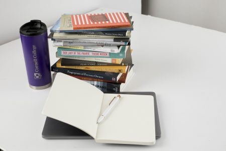 Bookes stacked up, open notebook, and Cornell College mug