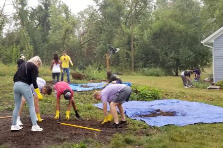 Several students help with derecho cleanup at a local home.