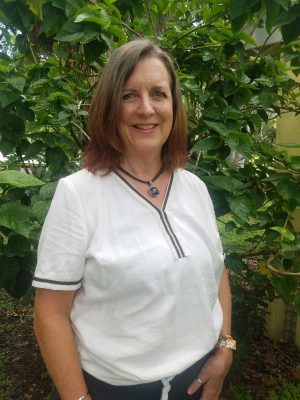 Ann McGregor, Class of 1984, poses in front of a green leafy backdrop at her home in Florida. 