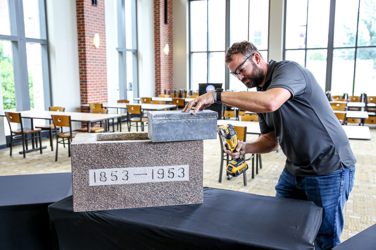 Facilities Operations Manager Director Luke Fischer breaks open the Field House time capsule that was placed in the cornerstone in 1953.