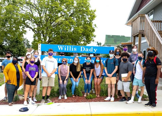 Housing is a Human Right classmates stand in front of the sign of Willis Dady Homeless Services