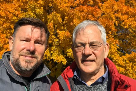 David Korslund ’76 (right) and his husband, Rob Kooiman, stand in front of trees in fall colors