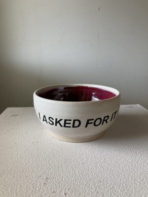 A ceramic bowl on a white stand with words "I asked for it."