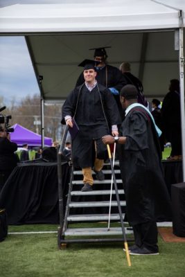 Alex Gillaspie walking down the stairs of the stage at graduation