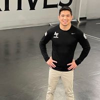 Wrestling Coach Chris Heilman '08 stands on the mat  at the U.S. Air Force Academy