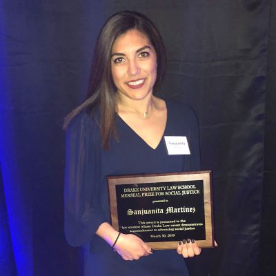 Sanjuanita “Sam” Martinez ’16 in a blue dress holding an award