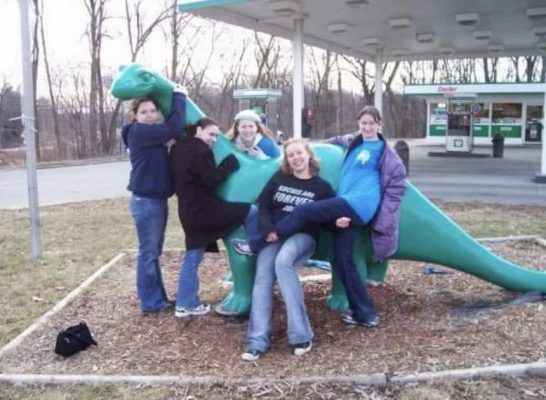 Five students pose with a Sinclair Dinosaur at a local gas station