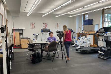 KCRG reporter interviews a student in a kinesiology lab with a video camera.