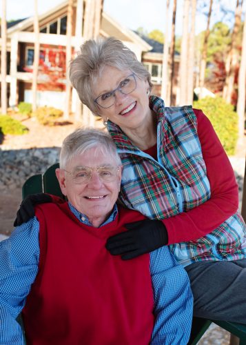 Nels Lindquist is seated and Cindy Ransom Lindquist leans in behind; they are dressed in reds and plaids for winter