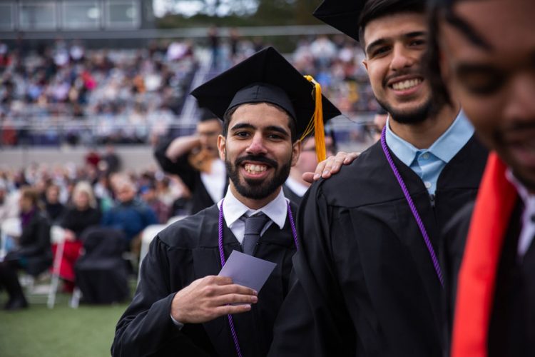 Friends Abdulla Awaji ’22 (left) and Aria Dehshid ’22 prepare to walk across the commencement stage.