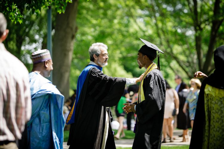 Professor of Economics and Business A’amer Farooqi warmly greets Abubakar Shehu ՚17, an international student from Nigeria, following Commencement.