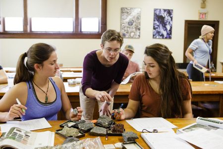 Professor of Geology Emily Walsh and two students examine rocks in the classroom
