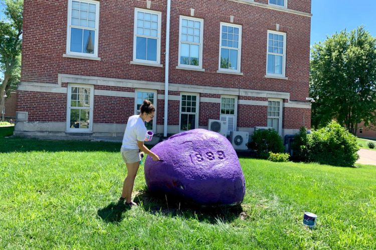 Julissa Rivera ’24 paints The Rock purple, of course, after it was moved next to Law Hall in summer 2022.