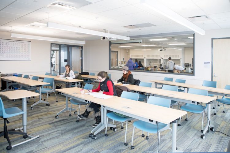 Students in a classroom in Russell Science, with a window behind them in which you can see a lab class