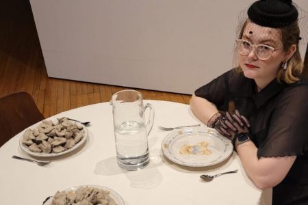 Annalisa sitting at a table with three plates, two filled with fortune cookies