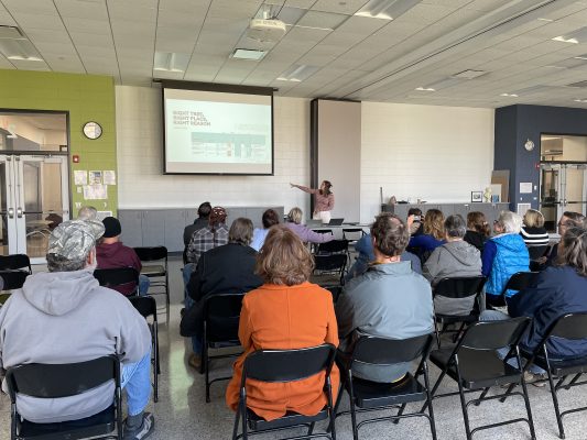 Kann presenting in front of a crowd at the third info session where the team passed out 23 tree vouchers. 