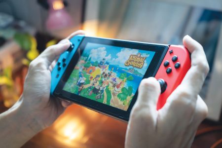 hands holding a Switch showing the Animal Crossing game