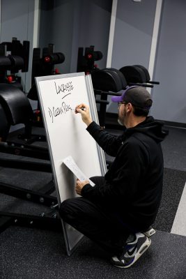 Lamb writing on a white board with the training plan for the day.