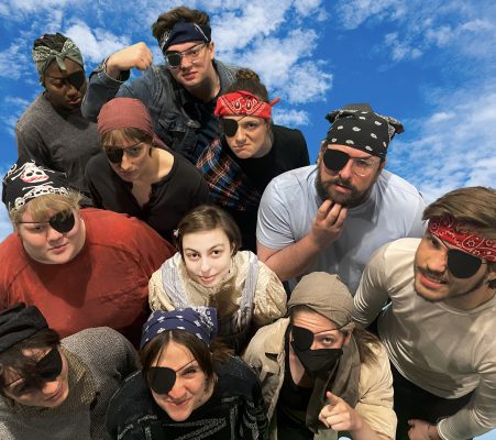 Cast of students in pirate costumes looking at the camera for a photo