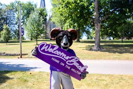 The Cornell College Ram mascot, Ulysses, holding a sign that says welcome back.