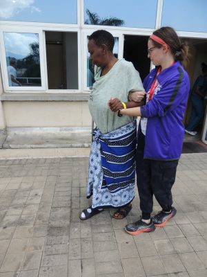 Elinor holding the arm of a patient who is walking along a path.