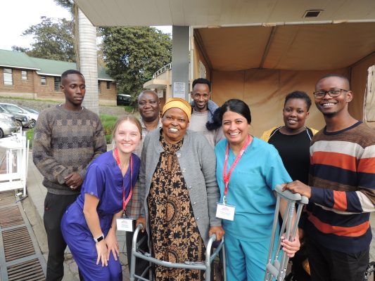 A family and two people in doctor scrubs smile for a photo.