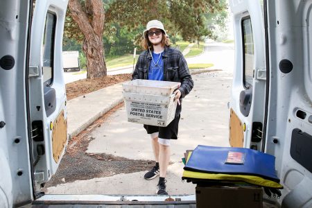 Will Ironside ’25 loads mail and packages in Frank, the mail van, before making campus deliveries. Photo by Megan Amr.