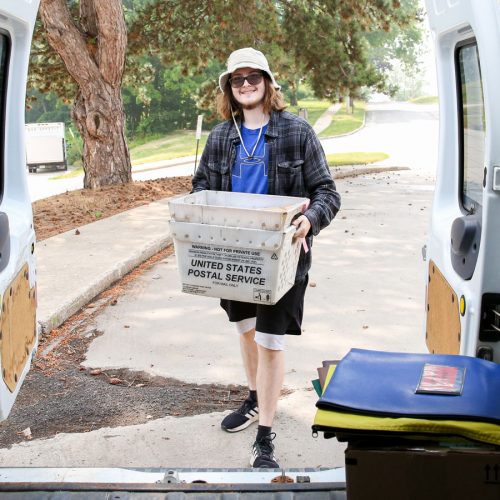 Will Ironside ’25 loads mail and packages in Frank, the mail van, before making campus deliveries. Photo by Megan Amr.