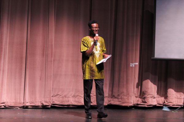 Henry Morray standing on stage with a microphone.