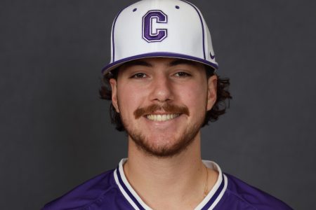 Jack smiles for a photo wearing a Cornell baseball cap and a purple jersey.