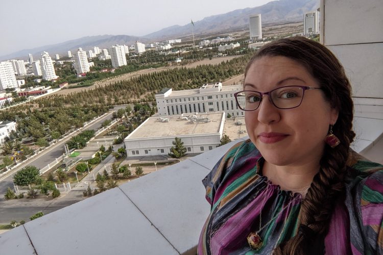 Emily Barbuto ’00 stands on the balcony of her apartment. Behind her are the Kopet Dag Mountains bordering Iran.