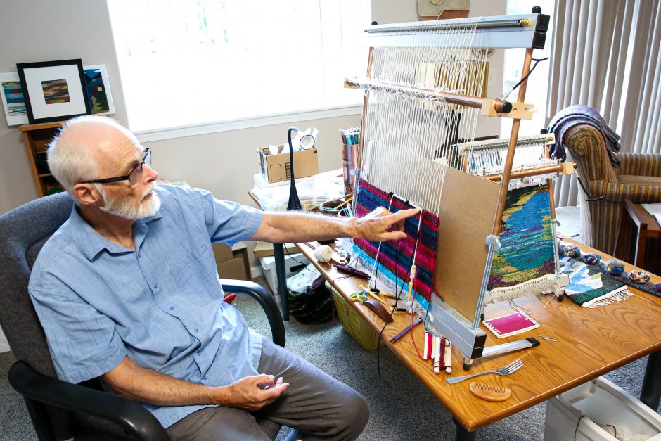 Chris Carlson points to his weaving work in process.