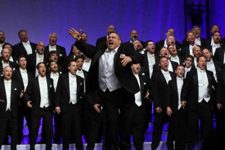 Barbershop singers in tuxes and arms in the air singing