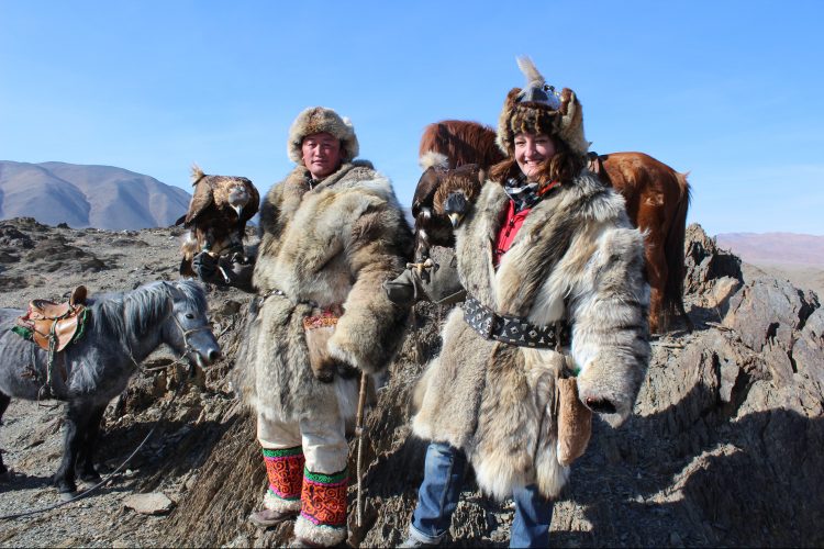 Julia Clark '06 wears traditional Mongolian coats with a falcon perched on her arm.