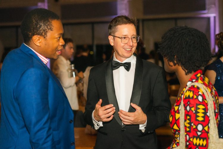 Kevin Rosser ’92 in a tux, speaking with two people at Oxford University, where he earned a masters degree.