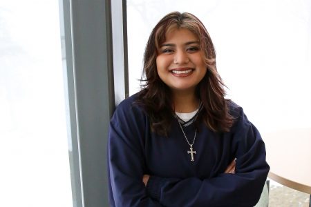 Posse Scholar Shirley Romero Carreon ’25 stands with arms crossed and a cross necklace.