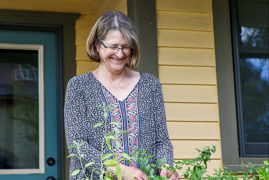 Suzette Astley tends to flowers in pots on her porch.