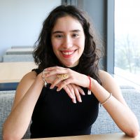 Claudia Collazo-Ramos sits at a desk smiling at the camera