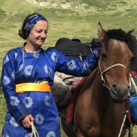 Julia Clark ’06 in traditional Mongolian dress with a horse in Mongolia