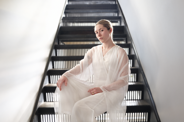 A girl wearing white sitting on a black set of stairs. 