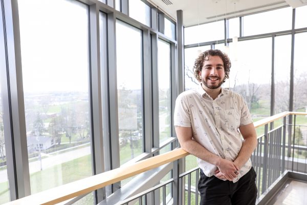 Ryan stands in front of a row of windows.