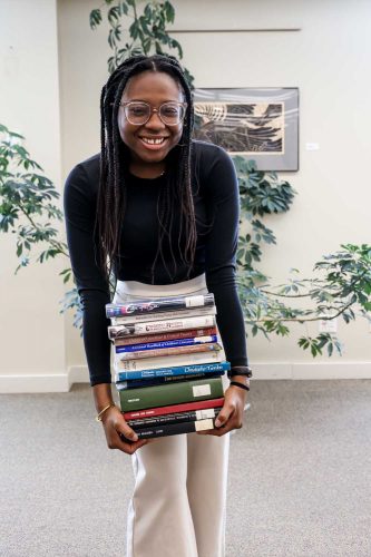 English-creative writing major Kimberly Maitland '24 holds a stack of books in Cole Library.