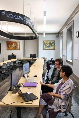 Senior Jake Vuolo sits in front of computer screens with Professor Santhi Hejeebu.