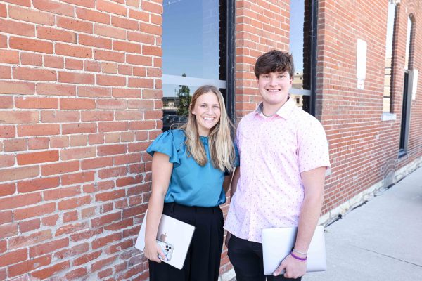 Krystin and Dakota pose for a photo outside the brick building where their internship is located in downtown Cedar Rapids.