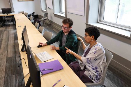 enior Jake Vuolo sits in front of computer screens with Professor Santhi Hejeebu.