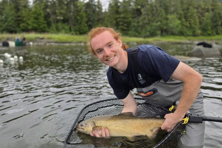 Student holds fish in a river