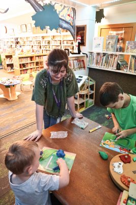 Nellie stands at a table where kids are working on a letter project.