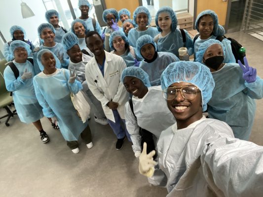 A group of students stand together in their hospital scrubs