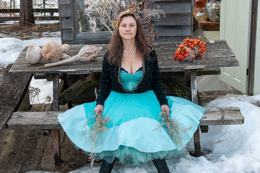 woman in turquoise dress sits on a picnic table in the snow